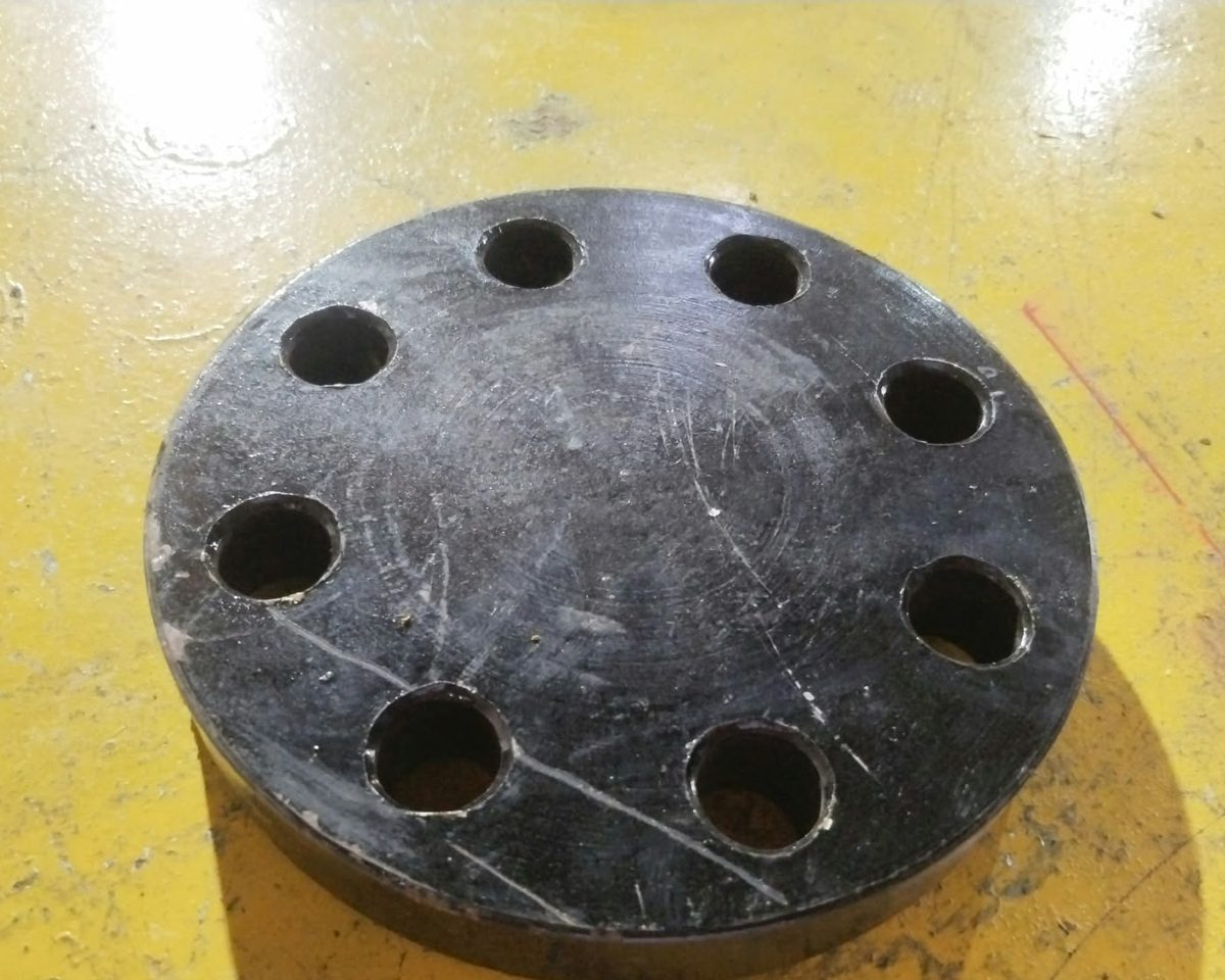 Carbon steel blind flange with eight bolt holes on the inspection table