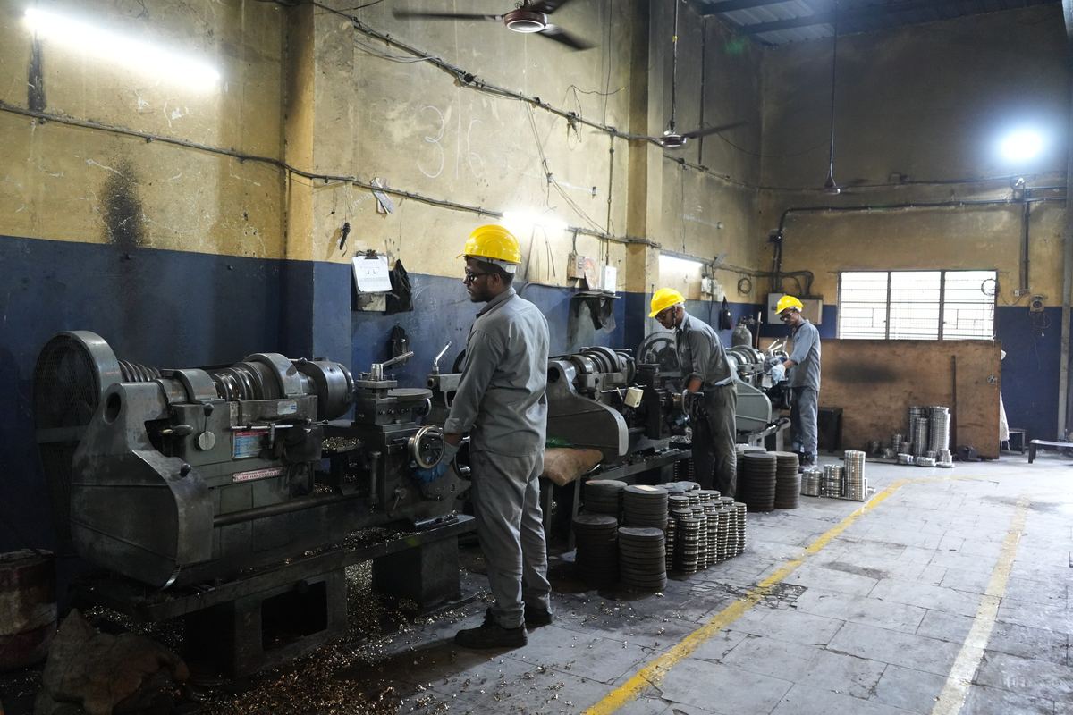 Row of conventional lathes with operators in the machine shop